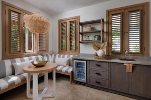 A modern kitchen with a built-in refrigerator, wooden cabinets, and a striped sofa.