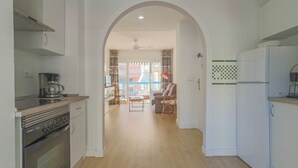 A kitchen with an oven, a coffee maker, and a refrigerator. There is a dining area with a table and chairs. - 080 - Gaviotas 004 - comfortHOLIDAYS (Santa Pola)