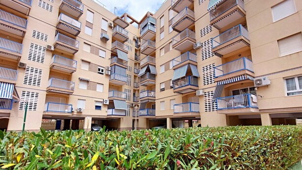 A multi-story residential building with balconies, air conditioning units, and a well-maintained hedge in the foreground. - 080 - Gaviotas 004 - comfortHOLIDAYS (Santa Pola)