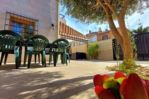 An outdoor patio area with green plastic chairs, a small tree, and a potted plant. - 082 - Gran Playa 005 - comfortHOLIDAYS (Santa Pola)
