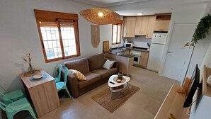 A modern living room with a sofa, coffee table, and a dining area with chairs. - 082 - Gran Playa 005 - comfortHOLIDAYS (Santa Pola)