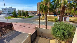 A residential area with a roundabout, palm trees, and a building with balconies. - 082 - Gran Playa 005 - comfortHOLIDAYS (Santa Pola)