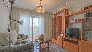 A living room with a sofa, a TV, wooden shelves, and a chandelier. - 084 - Isabel La Católica - comfortHOLIDAYS (Santa Pola)