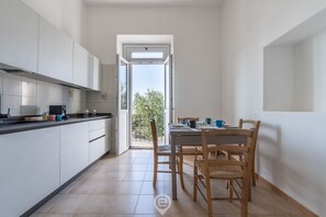 Une cuisine moderne avec des meubles blancs, un plan de travail noir et un coin repas comprenant des chaises et une table en bois.