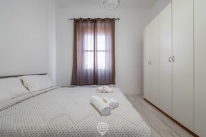 A bedroom with a bed, a wardrobe, and a window with curtains. - Port View Apartment - Cagliari (Cagliari)