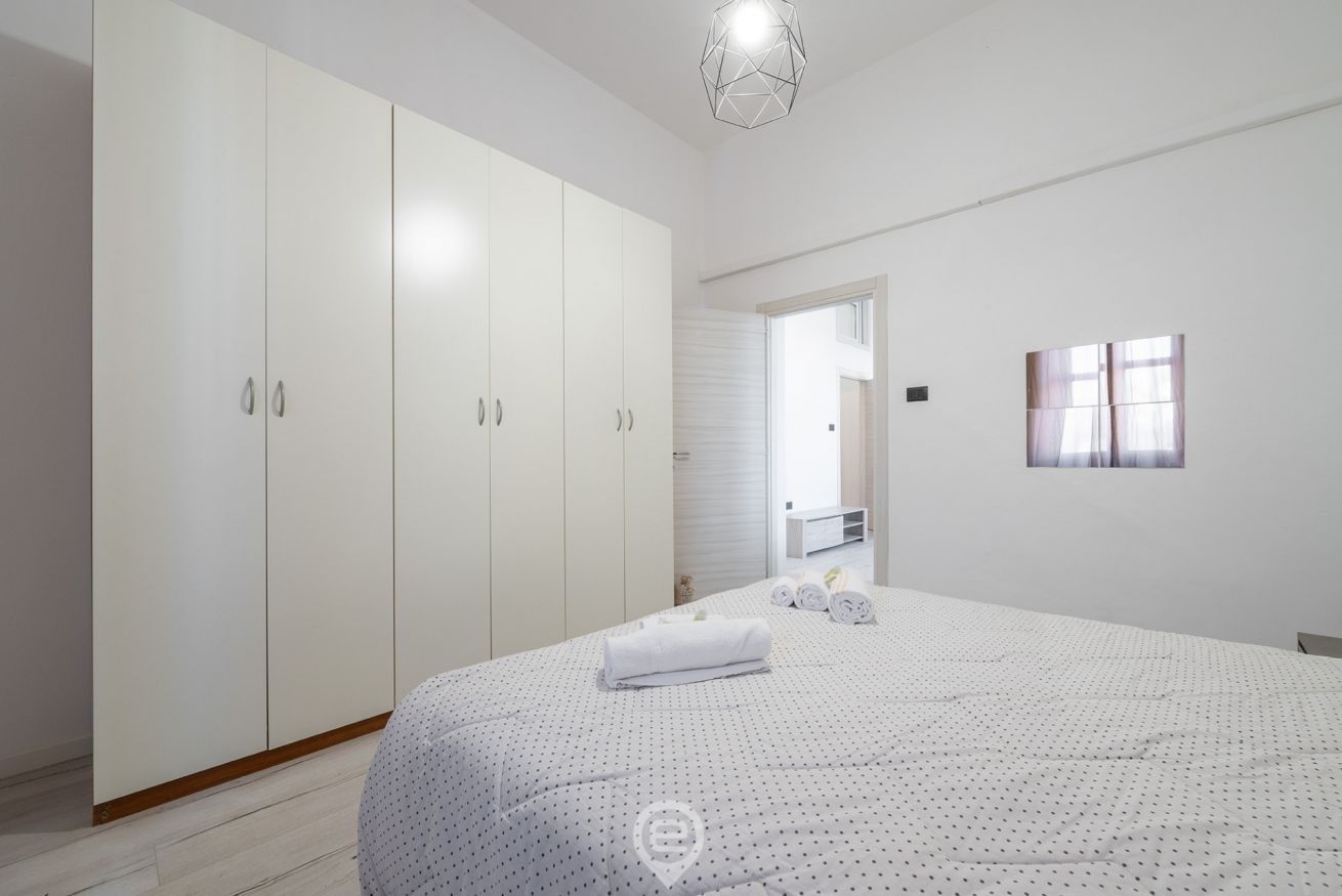 Una camera da letto con un letto grande, un armadio e un bagno visibile attraverso una porta aperta.