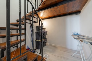 Een kamer met een houten trap, een werkbank en een naaimachine.
