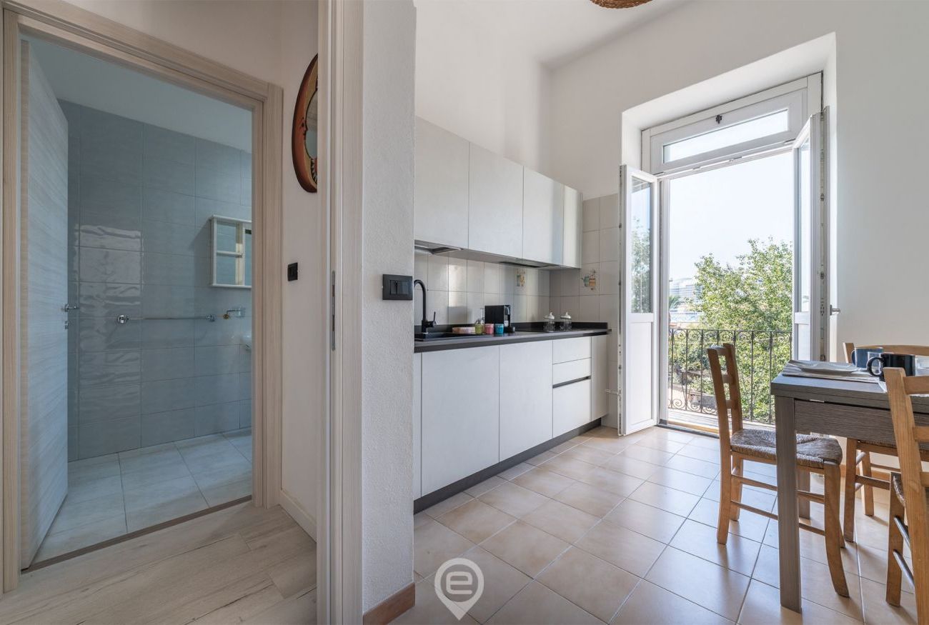 A modern kitchen with white cabinets, a black countertop, and a dining area with wooden chairs.