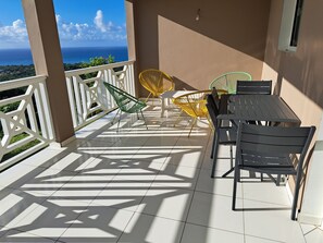 A balcony with a view of the ocean, featuring a table and chairs. - Villa LE Rocher (Le Diamant)