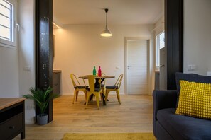Una stanza con un tavolo da pranzo, sedie, un divano, una lampada e una pianta.