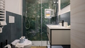 Un baño moderno con cabina de ducha de vidrio, un lavamanos blanco y un inodoro.