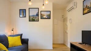 Un salón con sofá, un mueble para televisión y tres cuadros colgados en la pared.