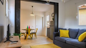 Una sala de estar con sofá, mesa de centro, televisor y un comedor con sillas y mesa.