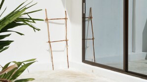 A room with a large sliding glass door, a hanging light fixture, and a wooden ladder leaning against the wall. - Casa Dantes Hotel & Spa (Nungwi)