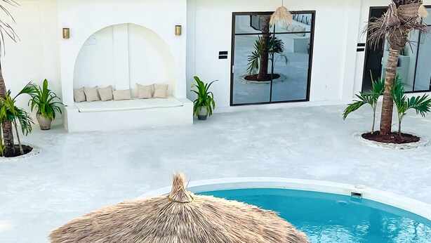 A circular pool with a thatched umbrella, surrounded by a white pool deck and potted plants. - Casa Dantes Hotel & Spa (Nungwi)