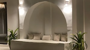 A modern, minimalist seating area with a semi-circular arch, two wall-mounted lights, and two potted plants. - Casa Dantes Hotel & Spa (Nungwi)