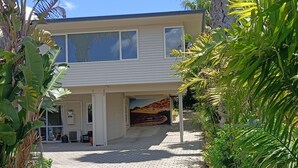 A modern two-story house with a paved driveway leading to a covered garage. - Iconic Wainui Beach a 100m stroll. Relax in Tropical type surroundings. (Gisborne)