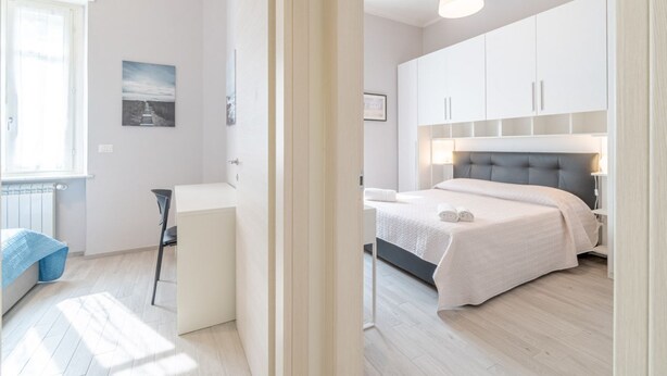 Un dormitorio con cama, mesita de noche y ventana.