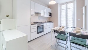 Una cocina moderna con armarios blancos, estufa a gas y comedor con mesa y sillas.