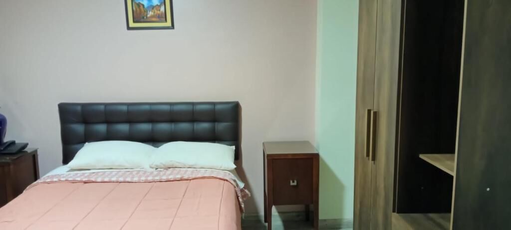 A bedroom with a bed, a nightstand, a wardrobe, and a door.