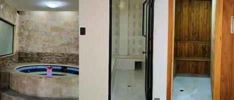 A bathroom with a stone wall, a bathtub, and a wooden door.