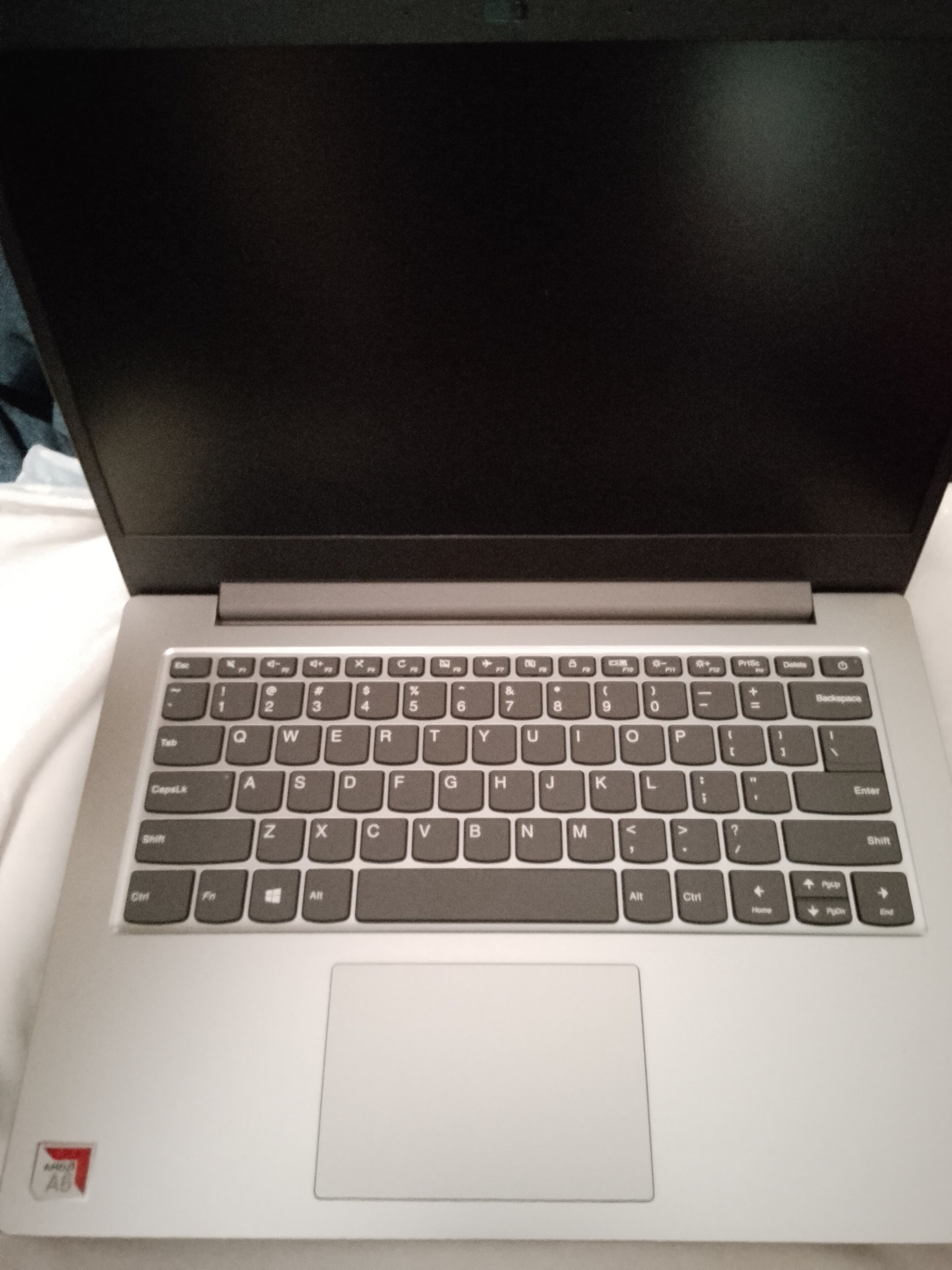 A laptop with a keyboard and trackpad on a white surface.