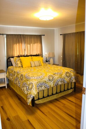 A bedroom with a bed, curtains, a nightstand, and a lamp. - Beautiful waterfront property (Chesterville)