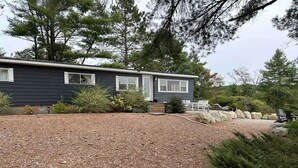 A house with a dark exterior, a front yard with mulch, and a small porch area. - Beautiful waterfront property (Chesterville)