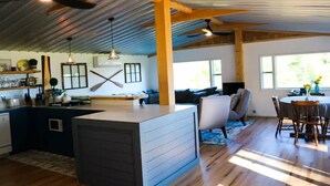 A spacious kitchen with a central island, wooden beams, and a dining area with a table and chairs. - Beautiful waterfront property (Chesterville)