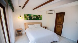 Un dormitorio con cama, mesita de noche, aire acondicionado de pared y puerta de madera.