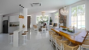 Un'ampia cucina con mobili bianchi, un'isola centrale e una zona pranzo con tavolo in legno e sedie in vimini.