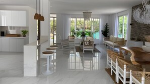 Una cucina moderna con mobili bianchi, un'area pranzo con tavolo e sedie in legno e un soggiorno con divano e tavolino.