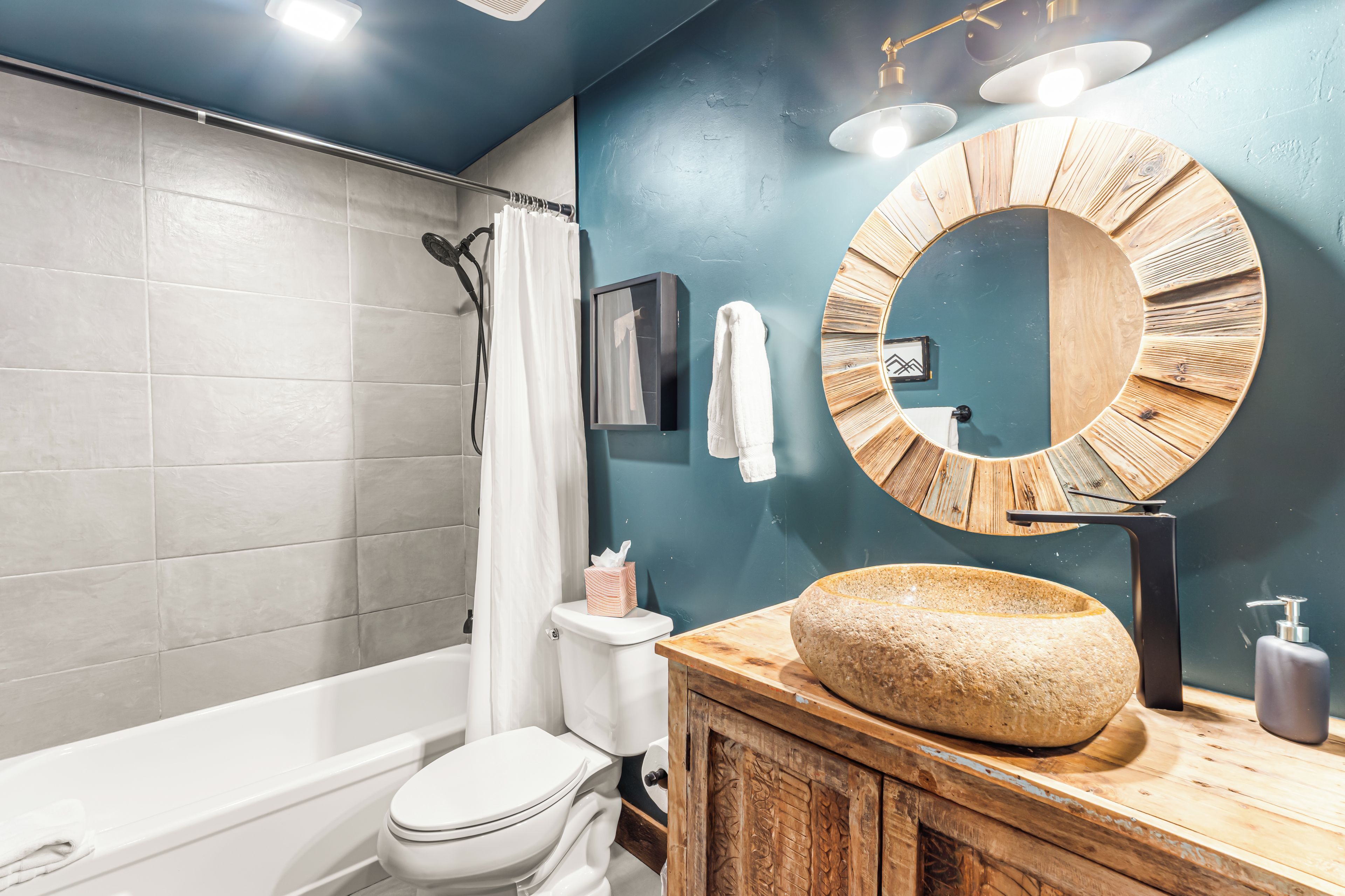 Une salle de bain équipée d’une baignoire, de toilettes et d’un meuble-lavabo en bois avec un vasque en pierre.