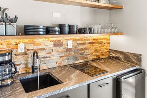 Una cocina moderna con protector mural de piedra, electrodomésticos de acero inoxidable y un lavamanos empotrado.