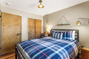 Un dormitorio con cama, armario de madera, cráneo de ciervo montado en la pared y una lámpara de pared.