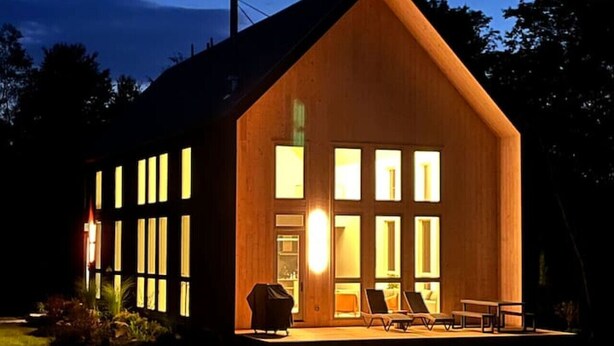Moderni puutalo, jossa on suuret ikkunat ja patio.