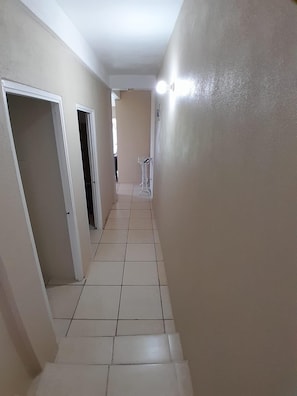 Leading to a space, this hallway features a neutral color palette and a small drying rack.