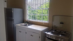 A compact kitchen with a refrigerator, sink, and stove. - 1 bedroom Apartment
 (Castries)