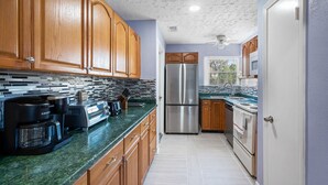 A kitchen with wooden cabinets, a stainless steel refrigerator, a coffee maker, and a microwave. - Sweet Home V - Family Cozy House, 20 minutes to downtown, 20 minutes to Airport (Houston)