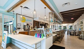 A modern bar and grill interior with a central counter, bar stools, and a glass display case. - 1840 Caribbean View Terrace (Kissimmee)
