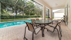 Relax by the pool in a serene outdoor space with a round table and six comfortable chairs.
