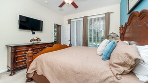 Relax in a spacious bedroom with a large bed, flat-screen TV, and two nightstands with lamps.