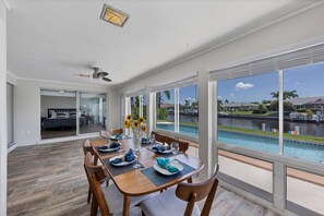 A dining area with a view of a swimming pool and a residential neighborhood. - 510 Matares Drive (Punta Gorda)