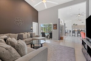 Relax in this stylish living space with a large L-shaped sofa, flat-screen TV, and dining area.