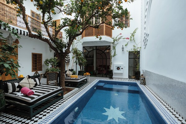 Une cour avec une piscine, un lit et un coin repas.