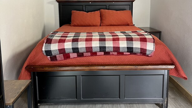 A bedroom with a bed, a nightstand, and a wooden headboard. - Studio Apartment in Wallace (Wallace)