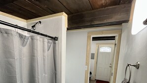 A narrow hallway with a shower curtain, a towel rack, and a door leading to a bathroom. - Studio Apartment in Wallace (Wallace)