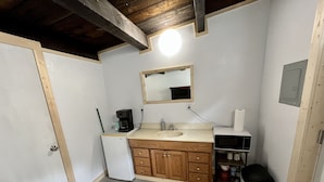 A compact kitchen with a wooden cabinet, a white refrigerator, a coffee maker, and a microwave. - Studio Apartment in Wallace (Wallace)