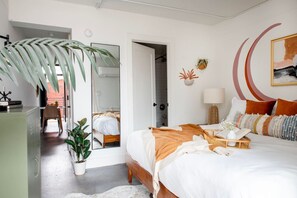 A modern bedroom with a large bed, a dining area, and a hallway leading to a bathroom. - The Audrey – Downtown Atlanta Apartment + Rooftop (Atlanta)