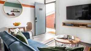 Un salon moderne avec un canapé bleu, une table basse ronde, un téléviseur et une porte portant le numéro 308.